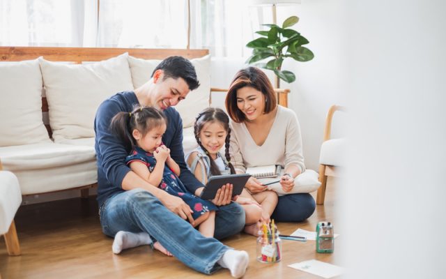 Happy Asian family using tablet, laptop for playing game watchin